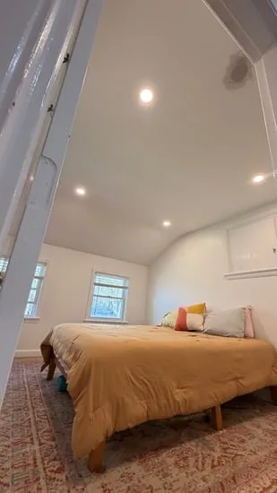 Finished recessed light installation Millis illuminating a main bedroom with a large bed.